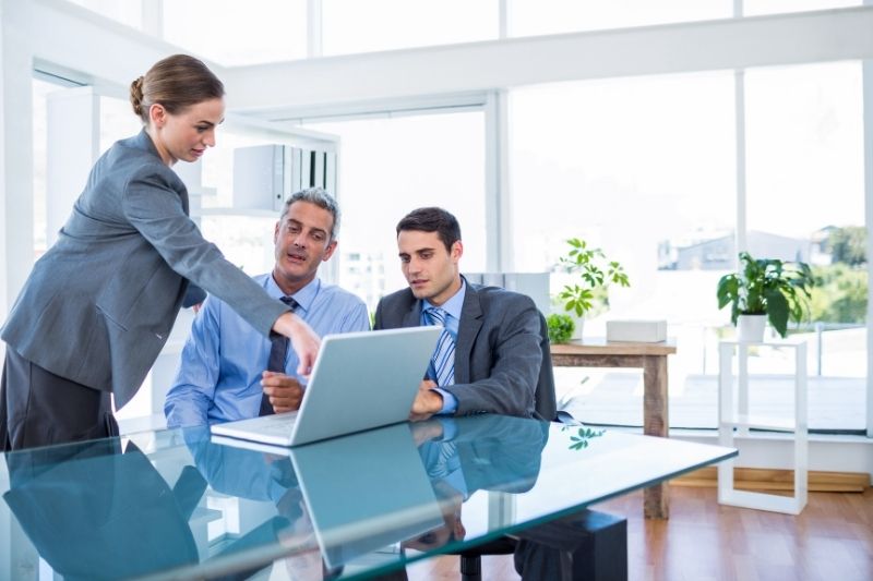 Consultores discutiendo estrategias de cumplimiento financiero en la oficina con un ordenador portátil.