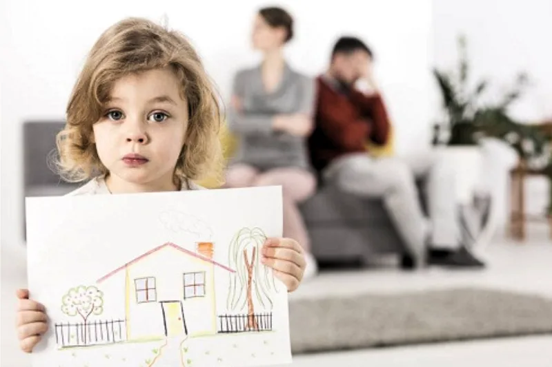 Niña sosteniendo un dibujo de una casa, simbolizando el impacto del divorcio y la custodia compartida en el entorno familiar.