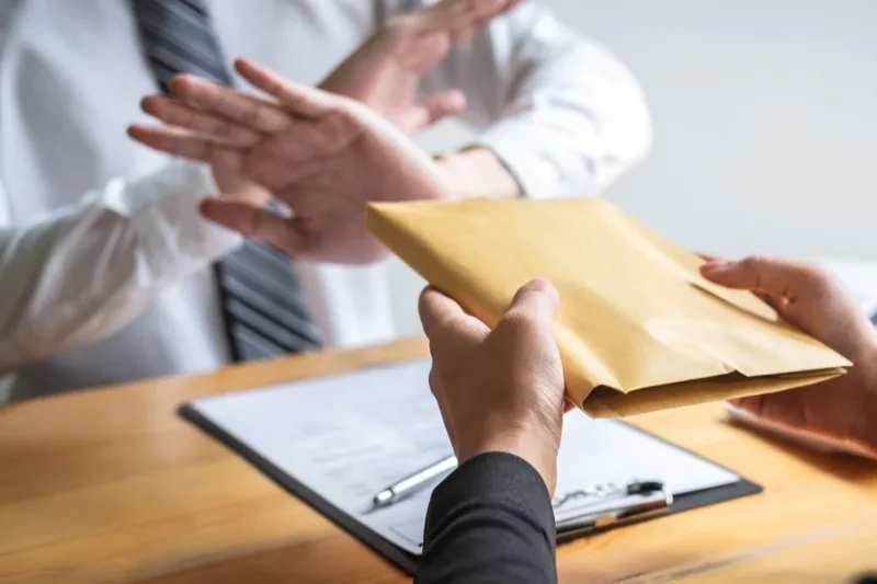 Persona rechazando un sobre con documentos legales sobre la mesa.
