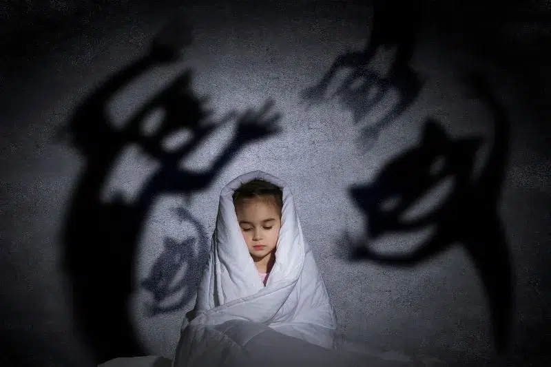 Niña bajo amenaza representada por sombras oscuras, simbolizando el peligro de la pornografía infantil generada por IA.