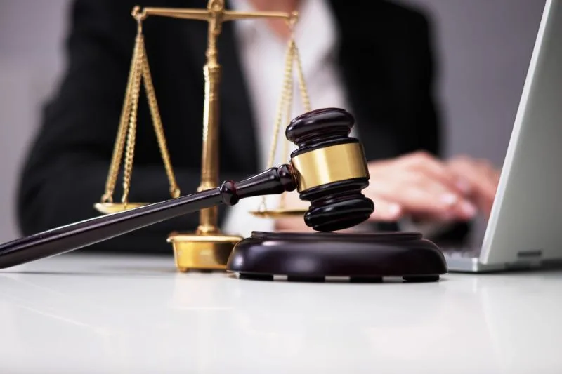 Juez con mazo y balanza de justicia en una mesa frente a un ordenador portátil, representando las reformas legislativas en derecho civil de 2025.