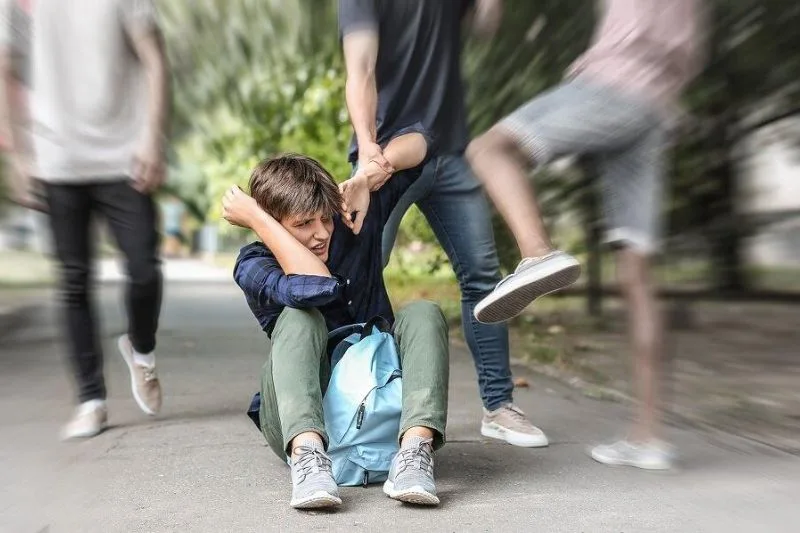 Adolescente siendo agredido en un espacio público por un grupo de jóvenes.