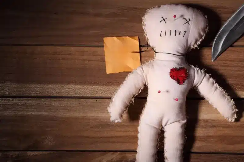Muñeco de trapo con alfileres, cuchillo y nota, simbolizando amenazas o delitos de odio